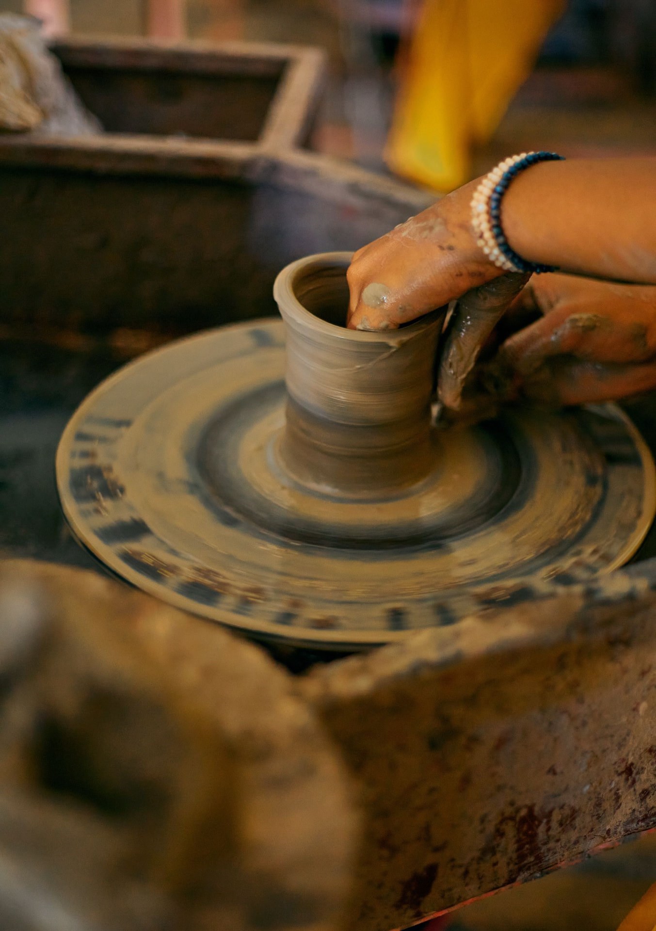 Hands shaping a clay pot on a potter's wheel