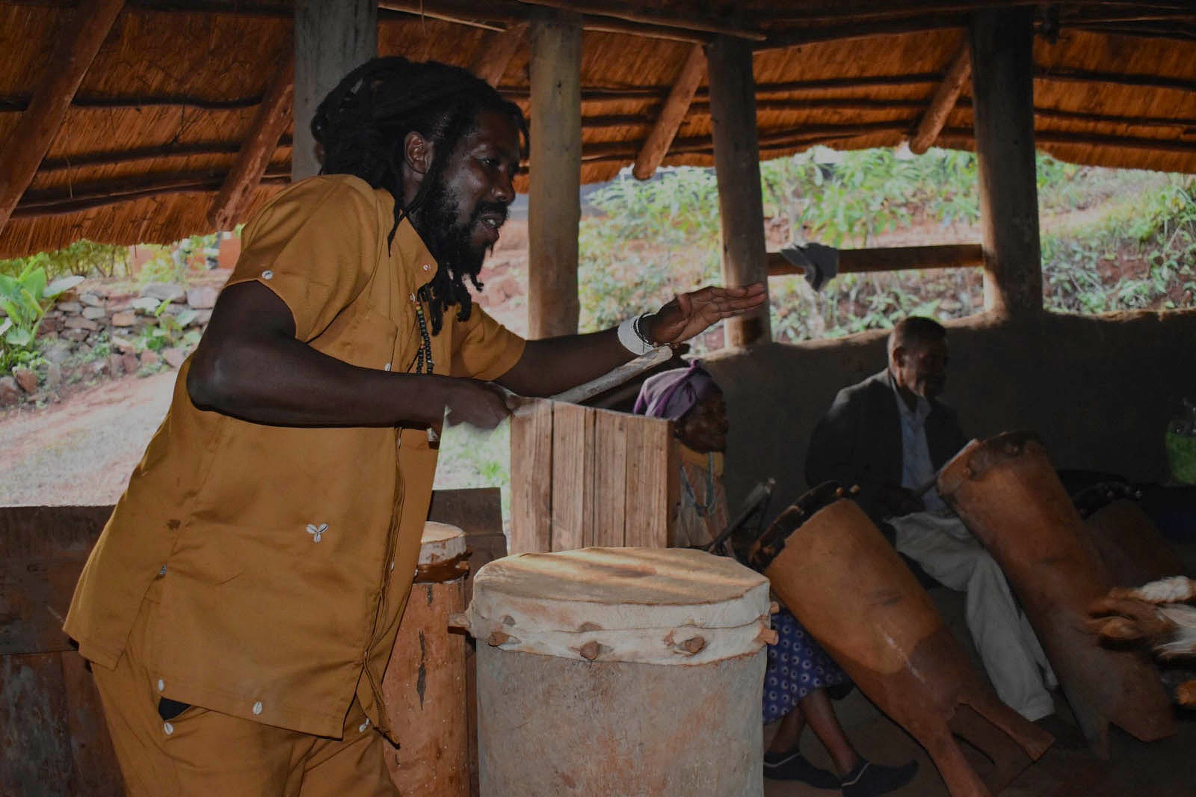 Villagers gathered around a fire at dusk as an mbira is played