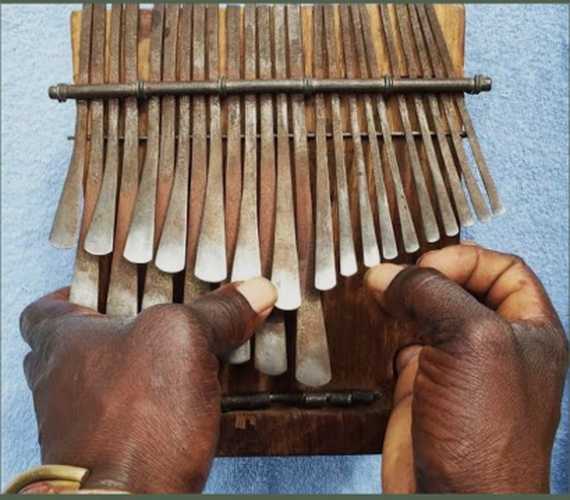 An mbira held in weathered hands
